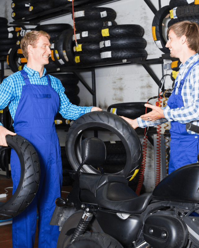 Two active adult coworkers mechanics working with new tires in workshop